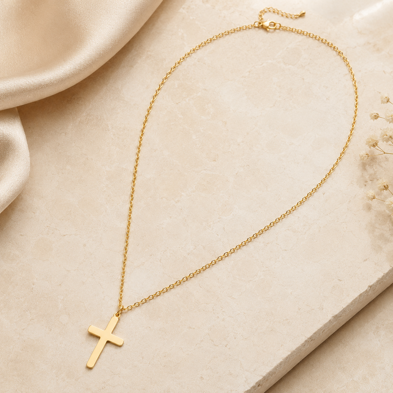 Gold-tone cross necklace styled on an ivory surface